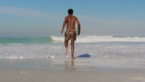 Surfista-Masculino-Corriendo-Hacia-El-Mar-En-La-Playa-4k