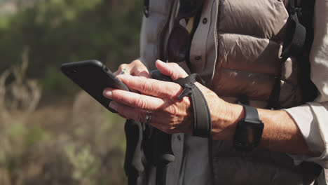 Close-up-view-of-senior-woman-holding-smartphone-in-forest