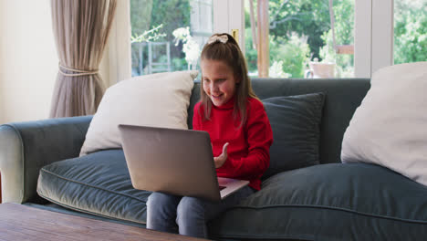 Kaukasisches-Mädchen,-Das-Einen-Video-Chat-Auf-Dem-Laptop-Führt,-Während-Es-Zu-Hause-Auf-Der-Couch-Sitzt