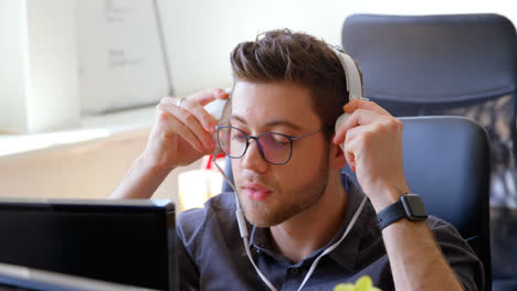 Front-view-of-young-caucasian-businessman-wearing-headset-and-working-at-desk-in-a-modern-office-4k