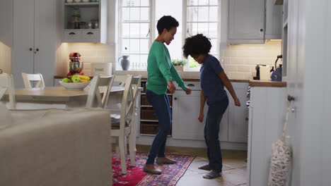 Mixed-race-female-couple-and-daughter-dancing-in-kitchen
