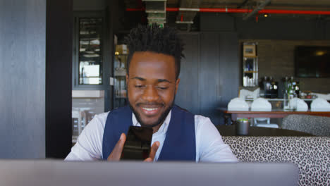 Front-view-of-young-black-businessman-with-laptop-talking-on-mobile-phone-in-a-modern-office-4k