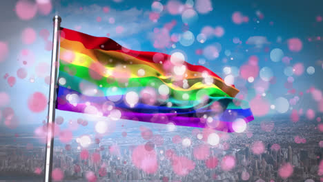 Animation-of-rainbow-flag-with-white-and-pink-flickering-spots-over-blue-sky-and-cityscape