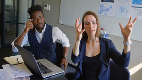 Side-view-of-young-mixed-race-business-team-planning-and-sitting-with-laptop-in-a-modern-office-4k