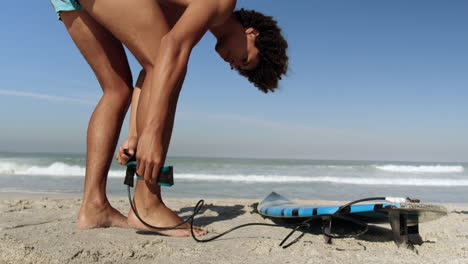 Young-male-surfer-tying-surfboard-leash-4k