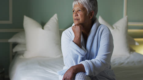 Ältere-Frau-Mit-Gemischter-Abstammung-Zu-Hause-Sitzt-Auf-Dem-Bett-Und-Denkt-Nach