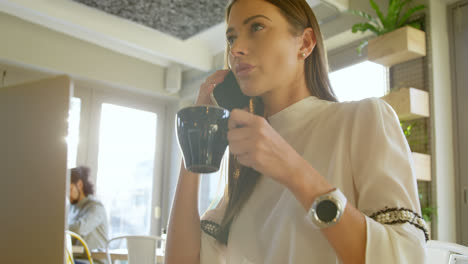 Executive-having-coffee-while-talking-on-mobile-phone-4k