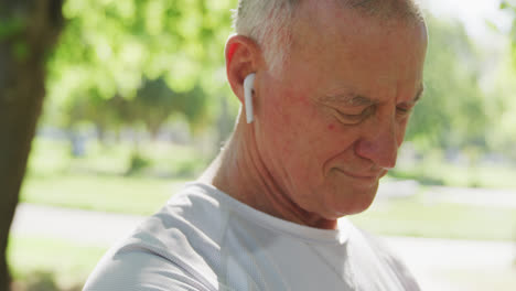 Senior-man-using-wireless-earphones-in-the-park