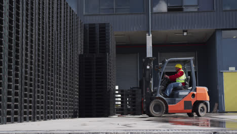 Warehouse-worker-driving-forklift-outside-factory