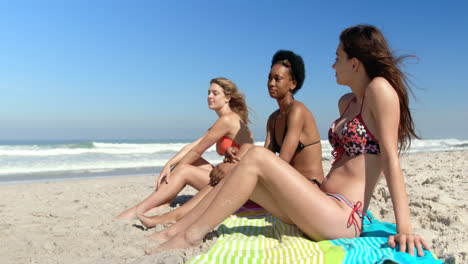 Young-female-friends-sitting-together-at-beach-4k
