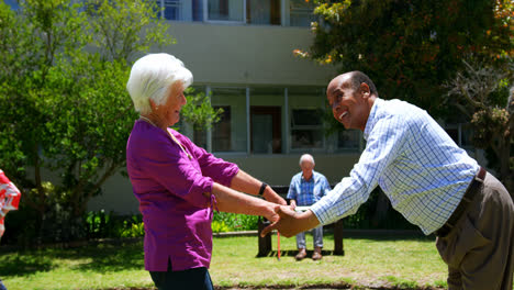 Side-view-of-active-mixed-race-senioar-couple-dancing-together-in-the-garden-of-nursing-home-4k