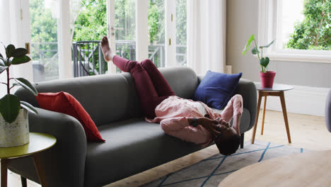 African-american-woman-talking-on-smartphone-while-lying-on-the-couch-at-home