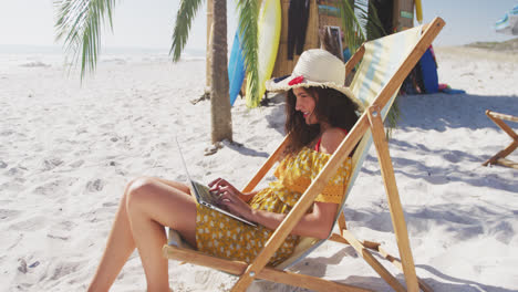 Kaukasische-Frau-Sitzt-Auf-Einer-Sonnenliege-Und-Benutzt-Ihren-Laptop-Am-Strand