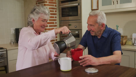 Senior-caucasian-couple-at-home-sitting-in-kitchen-having-breakfast