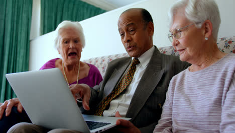 Group-of-active-mixed-race-senior-friends-discussing-over-laptop-in-nursing-home-4k