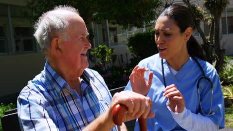 Front-view-of-active-Caucasian-senior-man-and-female-doctor-interacting-with-each-other-in-the-garde