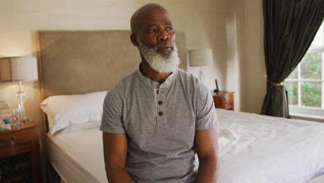 Thoughtful-african-american-senior-man-sitting-on-the-bed-at-home