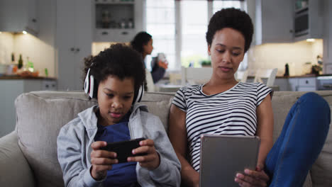 Mixed-race-mother-and-daughter-using-a-tablet-and-smartphone