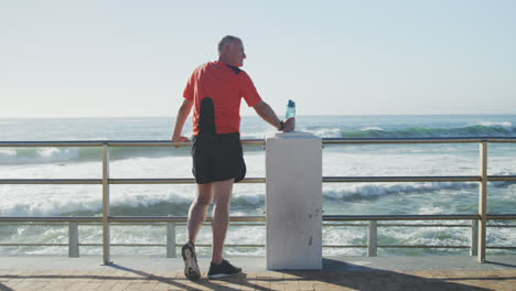 Senior-man-holding-water-bottle-standing-on-the-promenade