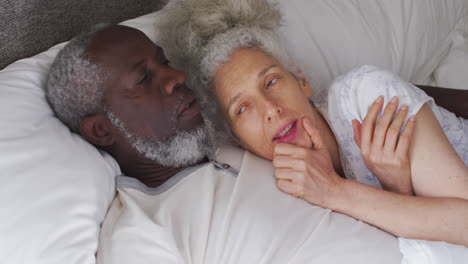 Mixed-race-senior-couple-sleeping-together-on-the-bed-at-home