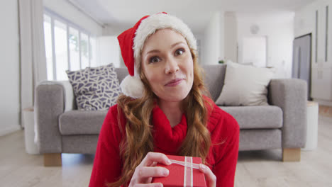 Überrascht-Eine-Frau-Mit-Weihnachtsmütze,-Die-Eine-Geschenkbox-öffnet,-Während-Sie-Zu-Hause-Einen-Videoanruf-Auf-Dem-Laptop-Führt