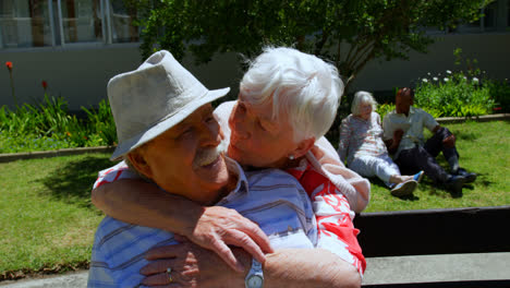 Vista-Frontal-De-Una-Pareja-De-Ancianos-Caucásicos-Activos-Abrazándose-En-El-Jardín-De-Una-Residencia-De-Ancianos-4k