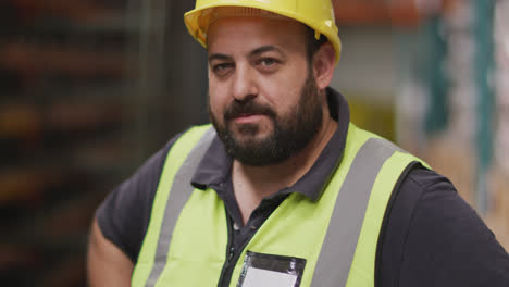 Caucasian-male-factory-worker-at-a-factory--wearing-a-high-vis-vest-and-a-hard-hat-standing
