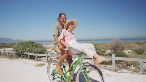 Senior-Caucasian-couple-riding-bikes-on-the-beach