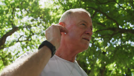 Senior-man-using-wireless-earphones-in-the-park