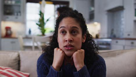Mixed-race-woman-sitting-on-couch-and-looking-annoyed