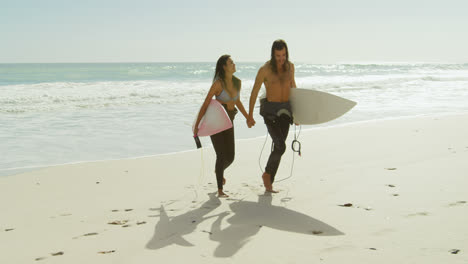 Couple-with-surfboard-walking-on-the-beach-4K-4k