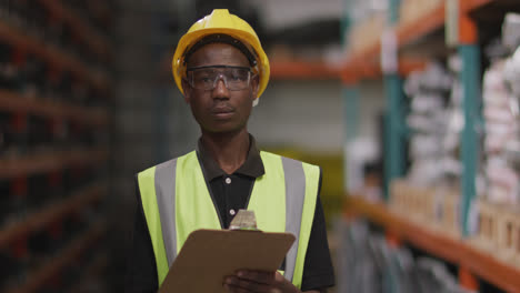 Afroamerikanischer-Fabrikarbeiter-In-Einer-Fabrik,-Der-In-Die-Kamera-Blickt-Und-Lächelt