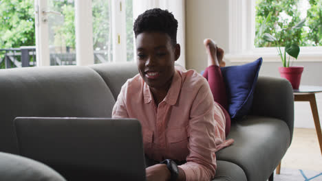 Afroamerikanerin-Benutzt-Laptop,-Während-Sie-Zu-Hause-Auf-Der-Couch-Liegt