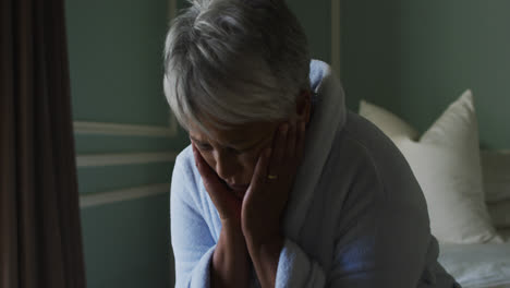 Depressed-senior-mixed-race-woman-at-home-with-head-in-hands
