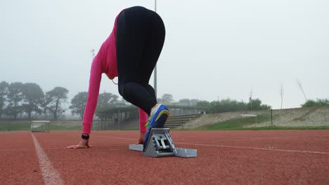 Rear-view-of-female-athlete-taking-starting-position-and-running-on-track-4k