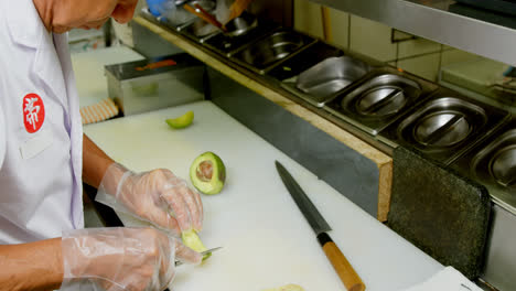 Male-chef-cutting-avocado-fruit-in-kitchen-4k