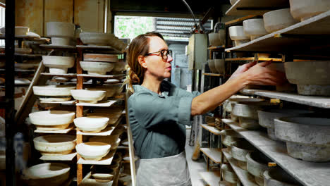 Female-potter-placing-bowl-in-shelf-4k