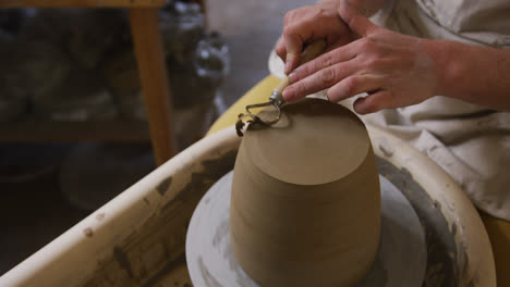 Close-up-view-of-female-potter-using-loop-tool-for-finishing-pottery-at-pottery-studio