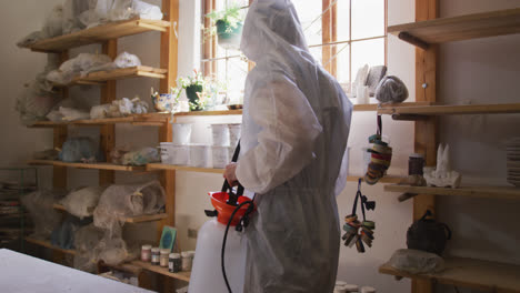 Heath-workers-wearing-protective-clothes-cleaning-and-sanitizing-pottery-studio-using-disinfectant-s