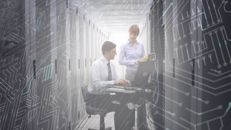 Man-and-woman-working-in-computer-server-room-while-a-glowing-circuit-board-moves-in-foreground-