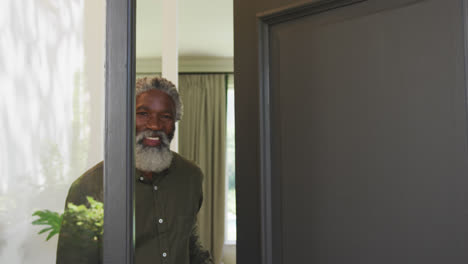 Älterer-Afroamerikanischer-Mann,-Der-Eine-Eingangstür-öffnet-Und-In-Die-Kamera-Blickt