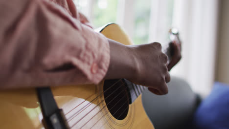 Close-up-of-african-american-woman-playing-guitar-at-home