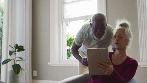 Älteres-Paar-Mit-Gemischter-Abstammung-Nutzt-Digitales-Tablet-Im-Wohnzimmer-Zu-Hause