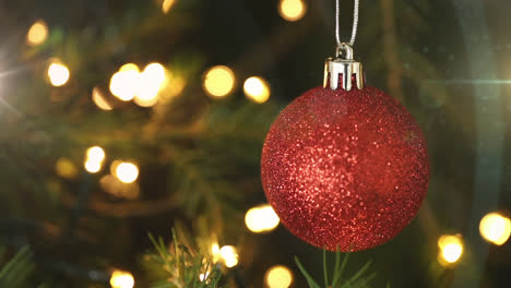 Digital-composition-of-spots-of-light-against-christmas-bauble-decoration-hanging