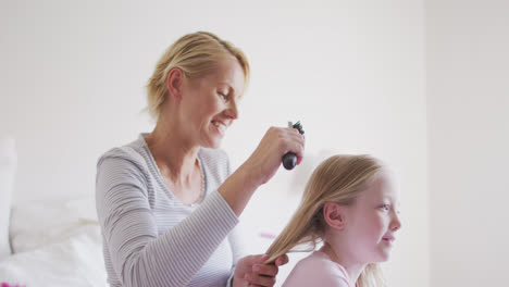 Side-view-of-Caucasian-woman-brushing-hair-of-her-daughter