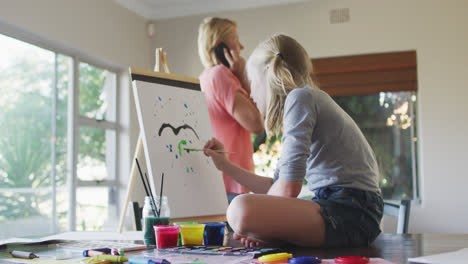 Side-view-of-Caucasian-girl-painting-with-her-mother-at-home