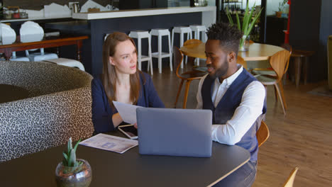 Front-view-of-young-cool-mixed-race-business-team-planning-and-sitting-at-table-of-modern-office-4k