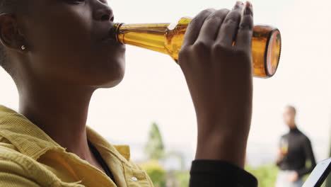 Junge-Afroamerikanische-Frau-Trinkt-Ein-Bier-Auf-Einem-Dach