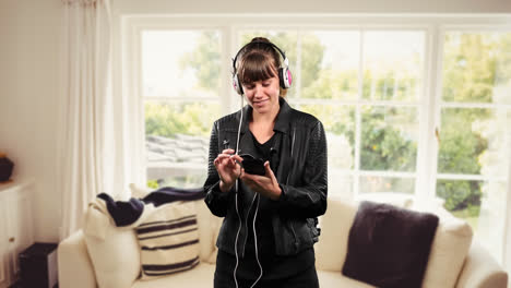 Caucasian-woman-listening-to-music-with-headphones-in-her-living-room-