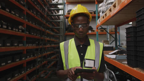 Afroamerikanischer-Fabrikarbeiter-In-Einer-Fabrik,-Der-Eine-Warnweste-Trägt-Und-Einen-Tablet-Computer-Verwendet